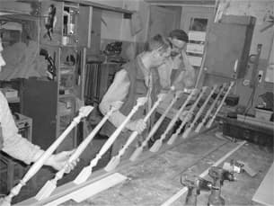 Craftsmen inspecting turned wooden balusters in our workshop